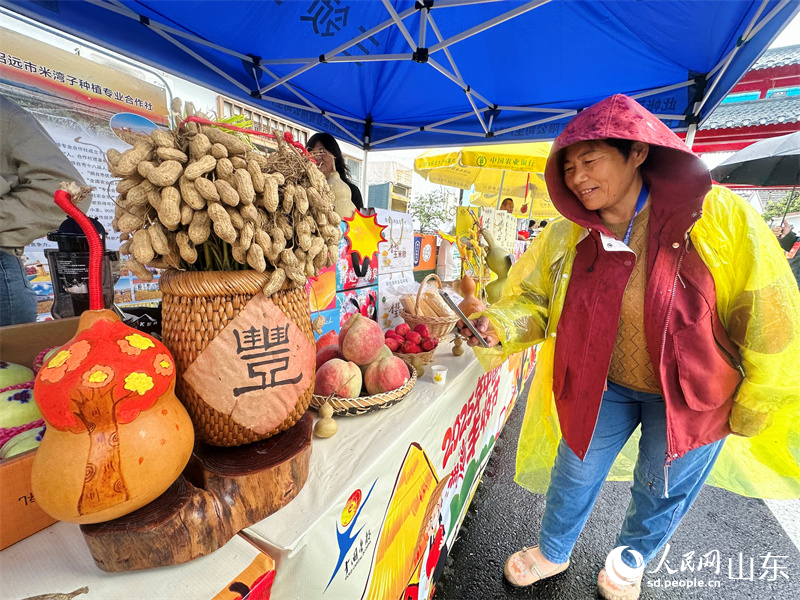 2025년 중국농민풍수절 전국 주요활동에서 방문객들이 시골장터에서 인증샷을 남기고 있다(인민넷 교주 촬영).